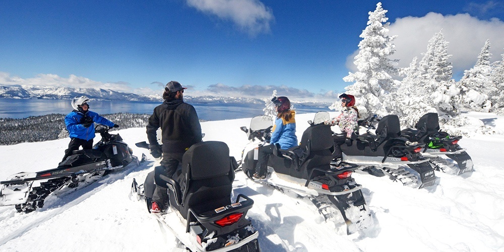 View of Lake Tahoe from the top of a snowy ridge on snowmobiles